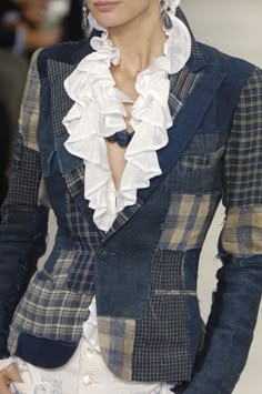 a woman with short hair wearing a blue jacket and white shirt on the catwalk