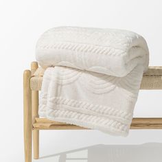 a white blanket sitting on top of a wooden bench