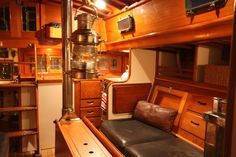 the inside of a wooden boat with lots of wood furniture and shelves on each side