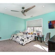 a bed room with a neatly made bed next to a window and a ceiling fan