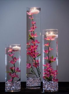 three vases with flowers and candles in them