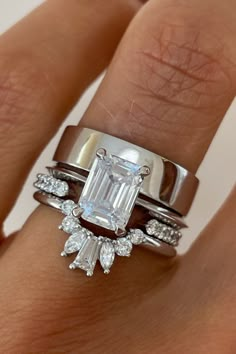 a woman's hand with two wedding rings and an engagement ring on her finger