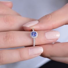 a woman's hand holding an engagement ring with a tanish blue stone