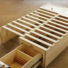 a wooden bed frame with drawers on the bottom and one drawer open to show what's inside