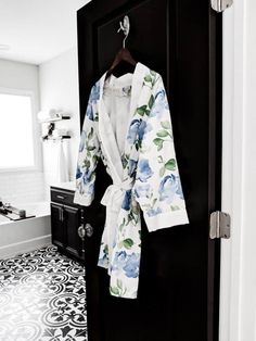 a robe hanging on a door in a bathroom with black and white tile flooring