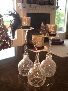 there are four wine glasses on the table with candles in front of it and a christmas tree behind them