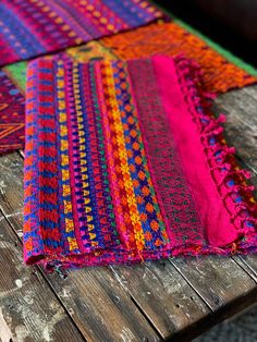 colorfully colored cloths are laid out on a wooden table with wood planks