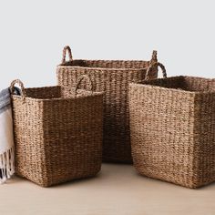 three woven baskets sitting on top of a wooden table