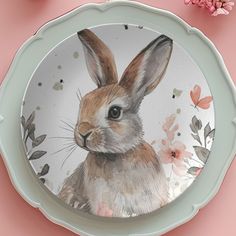 a plate with a painting of a rabbit on it and flowers in the back ground