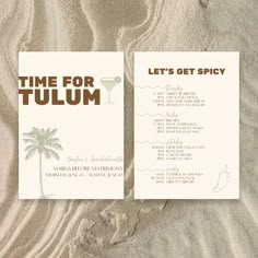 two business cards sitting in the sand with palm trees on it's back side