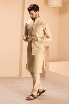 Light gold bundi featuring all over bahar bloom embroidery. Paired with a full sleeves kurta and Aligadhi pant., Fit: Relaxed Traditional Sleeveless Kurta For Reception, Designer Sleeveless Bandhgala With Zari Work, Fitted Chanderi Bandhgala For Reception, Designer Chanderi Nehru Jacket Fitted, Fitted Chanderi Nehru Jacket For Designer Wear, Traditional Nehru Jacket For Diwali Reception, Traditional Sleeveless Bandhgala With Resham Embroidery, Gold Bandhgala For Navratri Designer Wear, Ceremonial Chanderi Nehru Jacket For Diwali