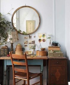 a desk with a mirror, chair and potted plant on it in front of a blue wall