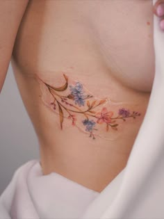 a close up of a woman's stomach with flowers on it and the bottom part of her breast