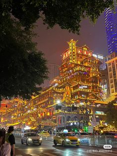 a city street at night with cars and buildings lit up in bright lights on both sides