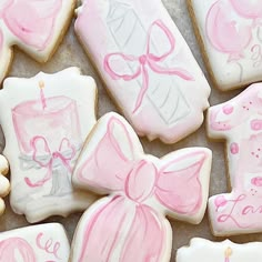 decorated cookies with pink and white icing are arranged on a table top, including one for the first birthday girl