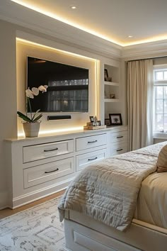 a bedroom with white furniture and a flat screen tv mounted on the wall