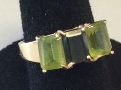 Beautiful Peridot 14K Yellow Gold Ring It is a size 6. Total weight of 3.3 grams solid 14K gold, stamped inside the ring. Features two rectangular peridot 12mm x 5mm and one rectangular dark green 12mm x 5mm center stone. I am unsure if it is an emerald? Or darker peridot. It is a beautiful ring and it will look beautiful on any one who wears it! Shipped insured/delivery confirmation I guarantee item to be exactly as described and pictured. Hallmarked Green Rectangular Rings, Hallmarked Green Rectangular Emerald Ring, Green Rectangular 14k Gold Ring, Rectangular Green Hallmarked Emerald Ring, 14k Gold Green Rectangular Ring, Rectangular Green 14k Gold Ring, Emerald Cut Peridot Ring In Green, Luxury Yellow Gold Peridot Rings, Rectangular Green Peridot Rings