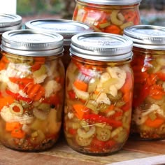 several jars filled with pickled vegetables on top of a wooden table