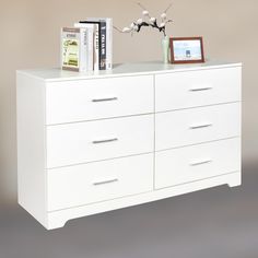 a white dresser with books and flowers on top