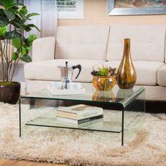 a glass coffee table sitting on top of a wooden floor next to a white couch