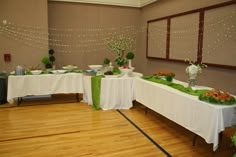 a banquet hall with tables covered in white tablecloths and green centerpieces