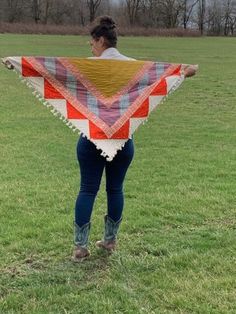 a woman standing in a field holding a quilt