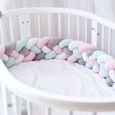 a white crib with a pink, blue and grey blanket