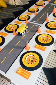 a table topped with lots of yellow and black traffic cones next to each other on top of a road