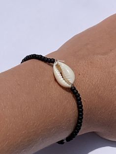 This is a beachy bracelet with a vsco shell and small beads. Cowrie Shell Beaded Bracelets As Gift, Trendy Handmade Beaded Strand Bracelets, Minimalist Black Jewelry For Beach, Minimalist Black Jewelry For The Beach, Beaded Bracelets For Beach Season, Beachy Handmade Strand Friendship Bracelets, Summer Shell Beaded Bracelets, Adjustable Shell Pearl Bracelet For Beach, Adjustable Black Stretch Bracelet For Beach