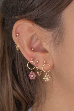 a close up of a person's ear wearing gold earrings with flowers on them