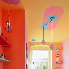 an orange and pink kitchen with colorful painted ceiling, potted plant on the window sill