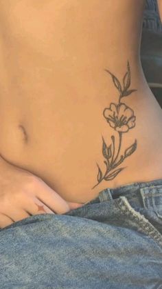 a close up of a person with a flower tattoo on their stomach and the bottom half of her body