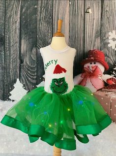 a white shirt and green tutu skirt on a mannequin stand in the snow