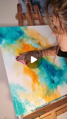 a woman is painting on an easel with paint