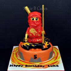 a birthday cake with an orange and red figure holding a gold stick on top of it