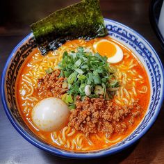 a bowl of ramen with an egg on top and some greens in the middle