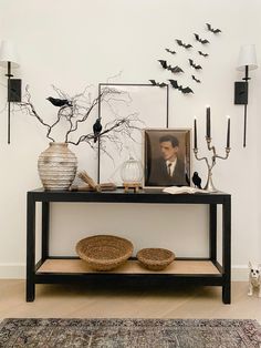 a black table topped with pictures and candles next to a wall filled with bats on it