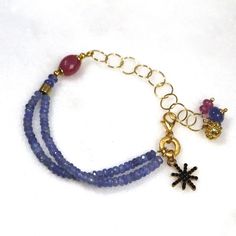 Glittering, vibrantly hued genuine polished natural periwinkle hued tanzanite, one of the rarest and most prized of all gemstones, sparkles on this strand in a beautiful bright striking splash of color! A plump faceted pink sapphire accents the side of the wrist. 14k gold fill chain and colorful drop embellishments add a little chic bling. l Blue Bracelets With Gemstone Accents As A Gift, Blue Bracelets With Gemstone Accents For Gift, Blue Bracelet With Gemstone Accents As Gift, Blue Amethyst Beaded Bracelets As Gift, Blue Amethyst Beaded Bracelets For Gift, Blue Amethyst Bracelets With Natural Stones, Lavender Tanzanite Jewelry For Gifts, Blue Amethyst Gemstone Bracelet, Party Multi-strand Faceted Beaded Bracelets