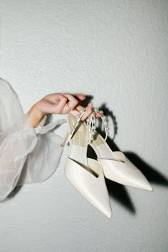 a woman is holding two pairs of shoes in one hand and an object in the other