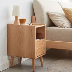 a wooden nightstand next to a bed in a room with white walls and flooring