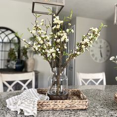 a vase filled with flowers sitting on top of a table next to a clock and napkins