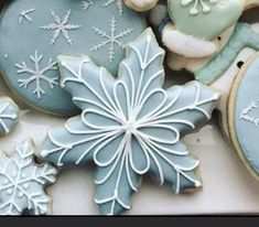 several decorated cookies are displayed on a white tablecloth with snowflakes and ornaments