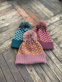 three knitted beanies sitting on top of a wooden floor next to each other