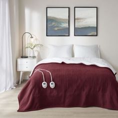 a bed with two pictures on the wall above it and headphones in front of it