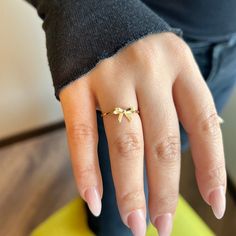 a woman's hand with a gold ring on top of her finger and a yellow object in the background