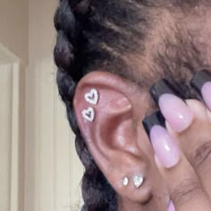 a close up of a person with ear piercings on their ears and one hand holding a cell phone to her ear