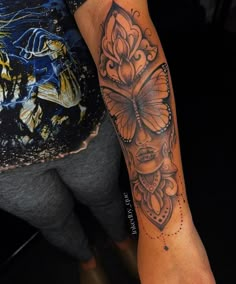 a woman's leg with a butterfly tattoo on it and an orange flower in the middle