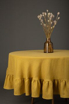 a vase filled with white flowers on top of a yellow table cloth covered tablecloth