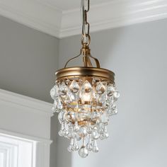 a chandelier hanging from the ceiling in a room with gray walls and white trim