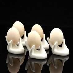 four white egg holders sitting next to each other on a black surface with reflections in the water